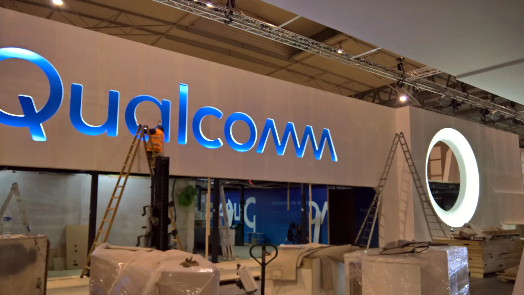 Stand de Qualcomm durante el montaje, con rotulación y paneles en proceso de instalación.